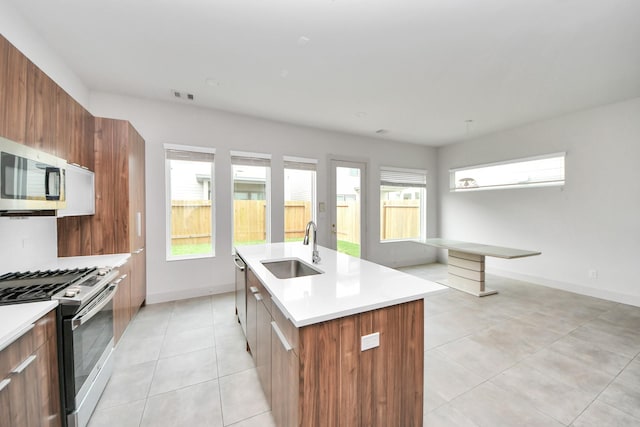 kitchen featuring a sink, an island with sink, stainless steel appliances, light tile patterned floors, and modern cabinets