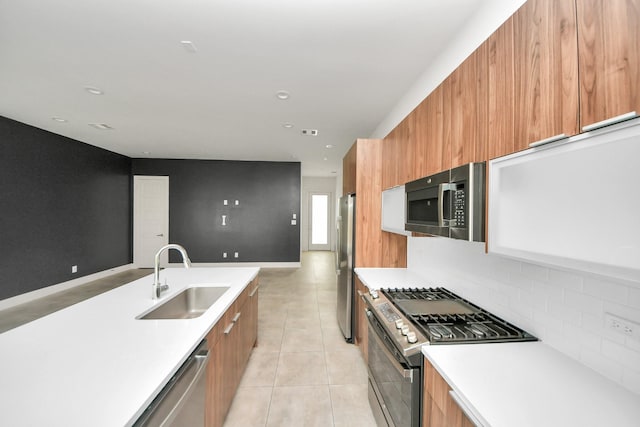 kitchen with appliances with stainless steel finishes, modern cabinets, brown cabinets, a sink, and open floor plan