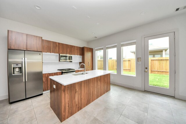 kitchen featuring appliances with stainless steel finishes, a sink, light countertops, an island with sink, and visible vents