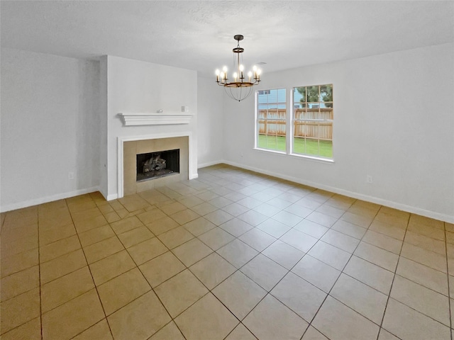 unfurnished living room featuring baseboards, a notable chandelier, light tile patterned flooring, and a fireplace
