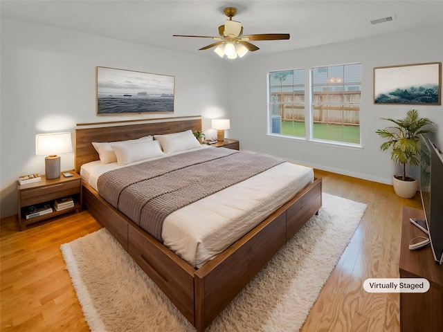 bedroom featuring baseboards, visible vents, ceiling fan, and light wood finished floors