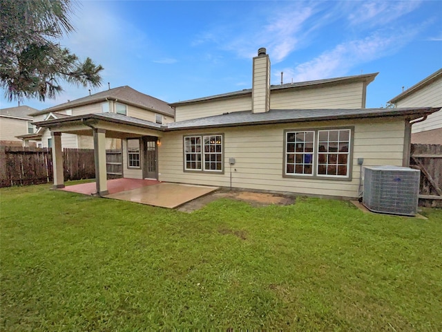 rear view of property with central AC, a fenced backyard, a chimney, a lawn, and a patio