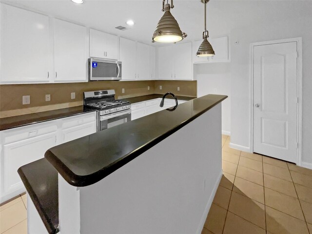 kitchen featuring stainless steel appliances, dark countertops, white cabinetry, and light tile patterned floors