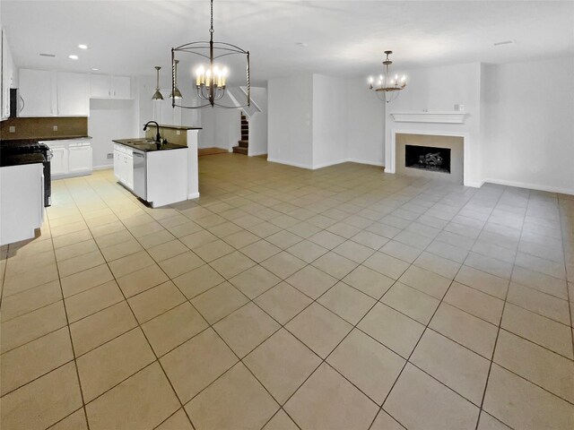 kitchen featuring dark countertops, dishwasher, a sink, open floor plan, and an inviting chandelier
