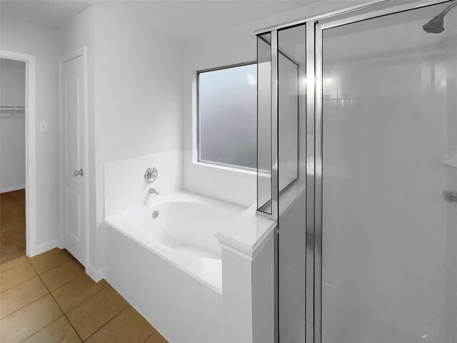 bathroom with tile patterned floors, a shower stall, baseboards, and a bath
