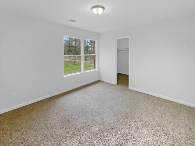 unfurnished bedroom with visible vents, carpet flooring, baseboards, and a spacious closet