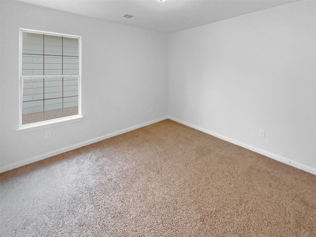 empty room with baseboards, carpet flooring, and visible vents