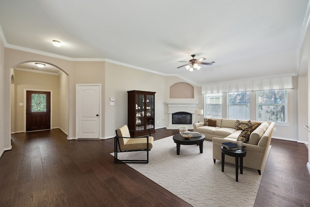 living area featuring a ceiling fan, arched walkways, healthy amount of natural light, a glass covered fireplace, and crown molding