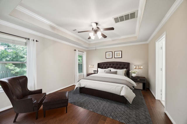 bedroom with a tray ceiling, dark wood finished floors, crown molding, ceiling fan, and baseboards