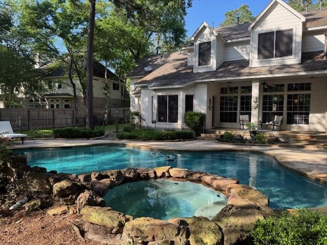 view of swimming pool featuring a patio, a pool with connected hot tub, and fence