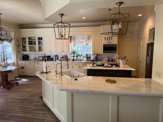 kitchen featuring a kitchen island, a notable chandelier, black refrigerator with ice dispenser, and a sink