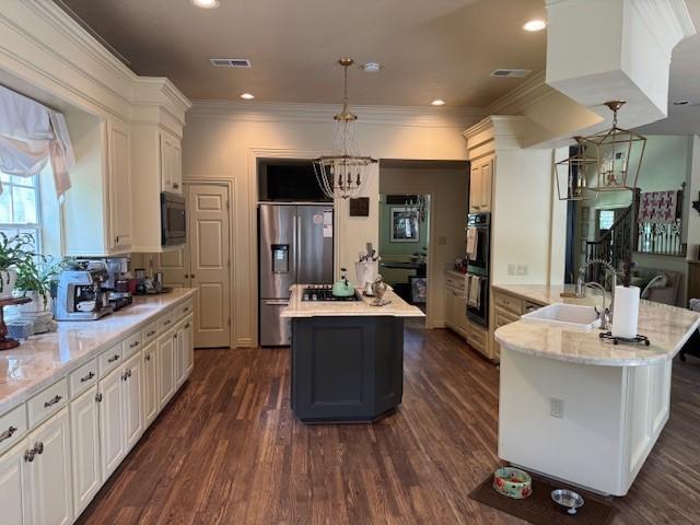 kitchen with visible vents, a center island, built in microwave, a sink, and stainless steel fridge