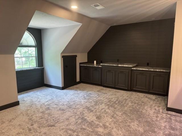 bonus room featuring light colored carpet, baseboards, vaulted ceiling, and visible vents