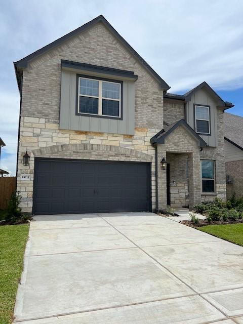 26712 Grandiflora Dr, Magnolia, TX 77355 - view of front of house featuring an attached garage, board and batten siding, driveway, and stone siding