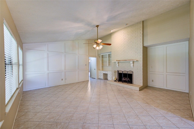 unfurnished living room with a brick fireplace, a decorative wall, ceiling fan, light tile patterned floors, and vaulted ceiling