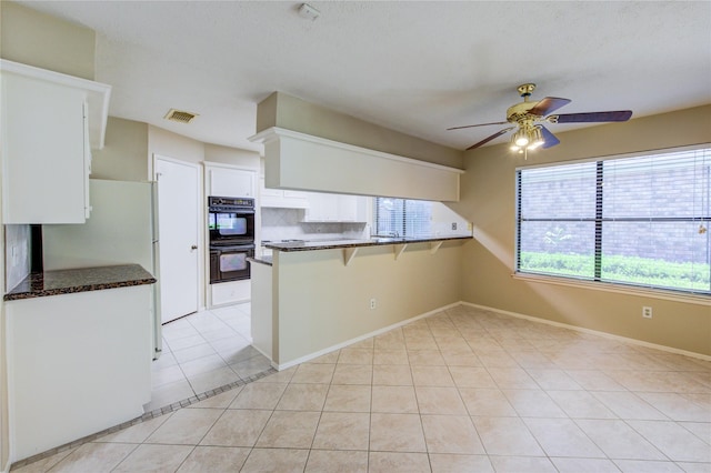 kitchen with dobule oven black, visible vents, a peninsula, white cabinetry, and a ceiling fan