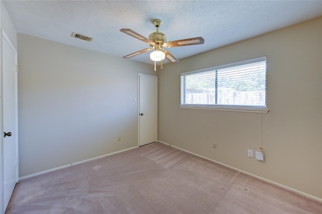 empty room featuring visible vents, baseboards, ceiling fan, and light colored carpet