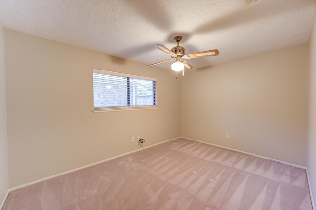 empty room with baseboards, light carpet, a ceiling fan, and a textured ceiling