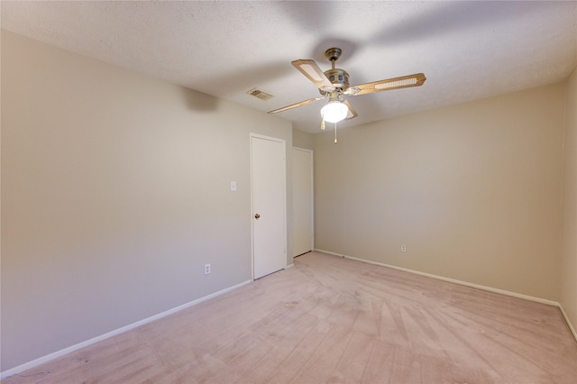 spare room featuring ceiling fan, visible vents, light carpet, and baseboards