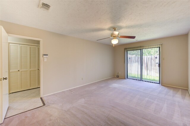 carpeted spare room featuring baseboards, ceiling fan, a textured ceiling, and visible vents
