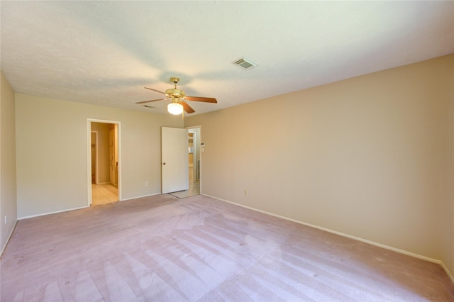 unfurnished room featuring baseboards, a ceiling fan, light colored carpet, and visible vents