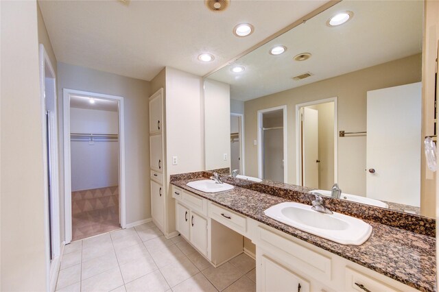 bathroom with tile patterned floors, visible vents, a sink, and a spacious closet