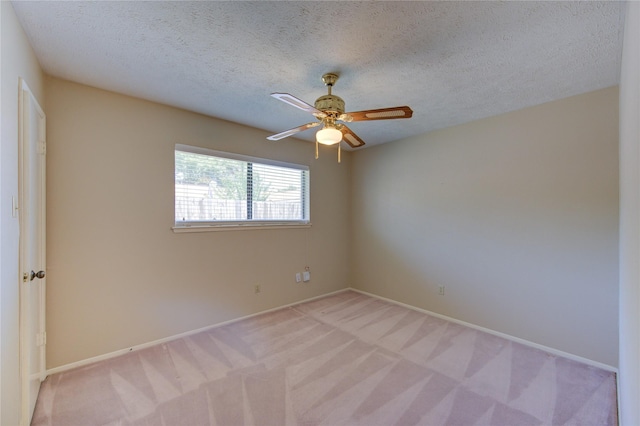 empty room with a ceiling fan, baseboards, light colored carpet, and a textured ceiling
