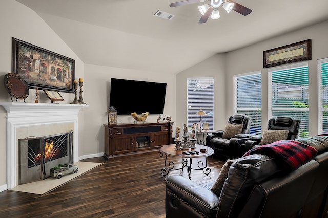 living room featuring ceiling fan, visible vents, dark wood finished floors, a fireplace with flush hearth, and vaulted ceiling