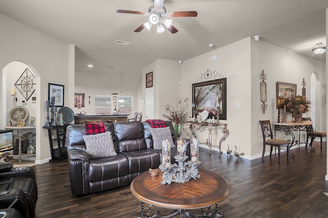 living area with arched walkways, a ceiling fan, baseboards, wood finished floors, and visible vents