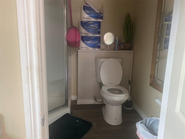 bathroom featuring toilet, baseboards, a shower stall, and wood finished floors