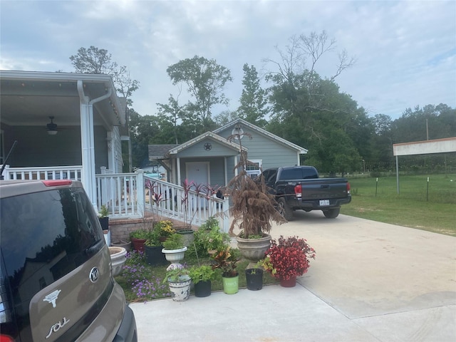 bungalow-style home featuring a porch, driveway, a ceiling fan, and a front lawn