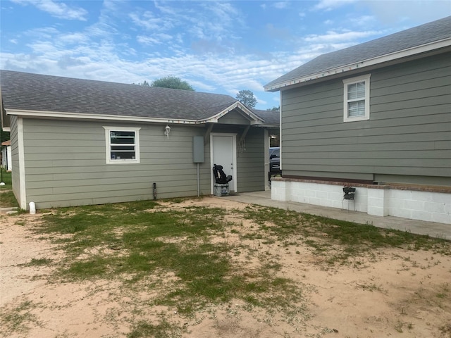 back of house featuring a shingled roof