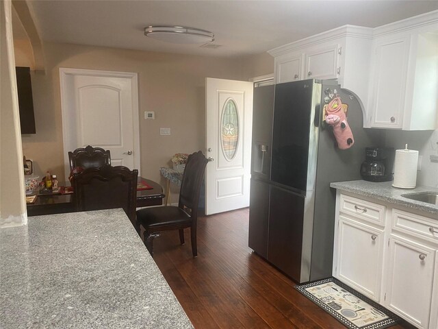 kitchen with stainless steel fridge, a sink, light countertops, dark wood finished floors, and white cabinetry