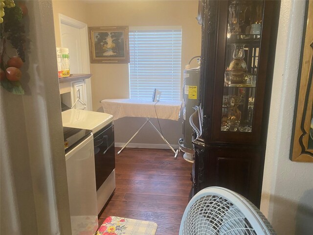 interior space with baseboards, dark wood-style floors, washing machine and dryer, and water heater