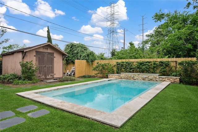 view of pool with a lawn, an outdoor structure, a fenced backyard, and a storage unit
