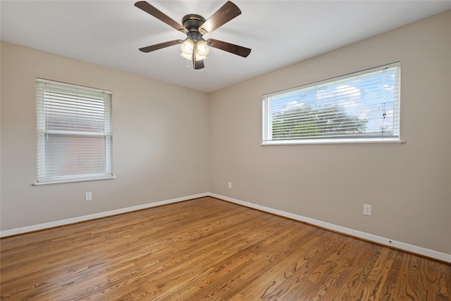 empty room with baseboards, ceiling fan, and wood finished floors