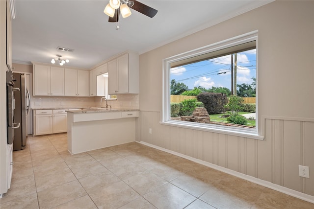 kitchen featuring a sink, light tile patterned floors, crown molding, and a peninsula
