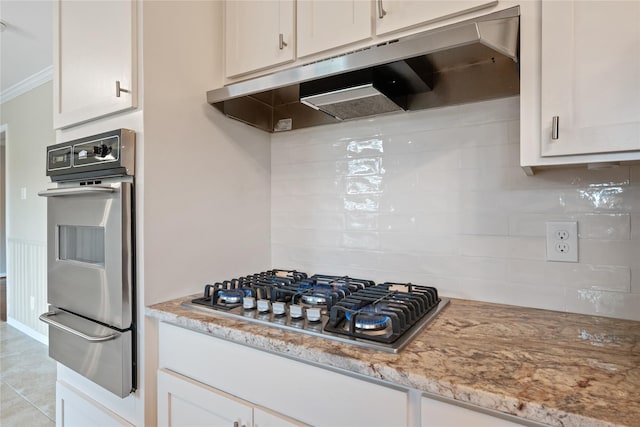 kitchen with under cabinet range hood, stainless steel appliances, backsplash, and a warming drawer