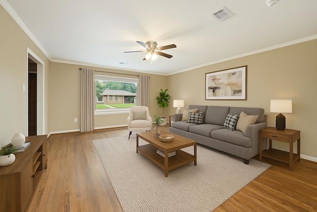 living room featuring a ceiling fan, visible vents, baseboards, light wood-style floors, and ornamental molding