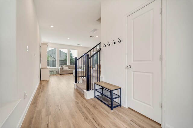 hallway with recessed lighting, stairway, baseboards, and light wood finished floors
