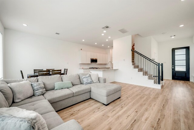 living area featuring stairway, recessed lighting, light wood finished floors, and visible vents