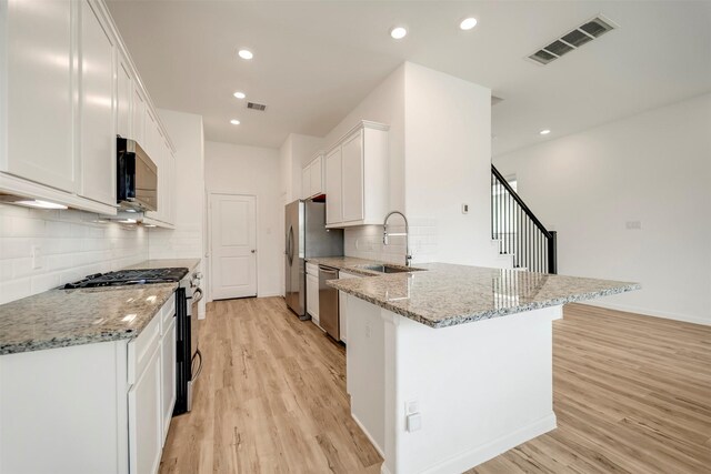 kitchen featuring visible vents, appliances with stainless steel finishes, light wood-type flooring, a sink, and a peninsula