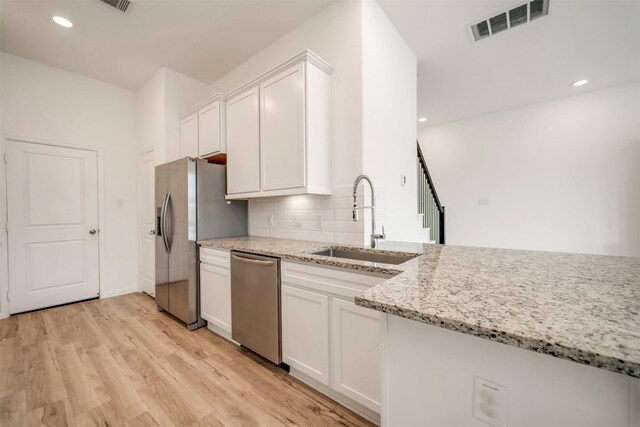 kitchen with white cabinets, a sink, light wood-style floors, stainless steel appliances, and visible vents