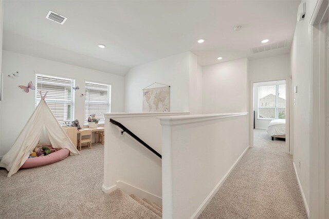 hall with an upstairs landing, light carpet, and visible vents