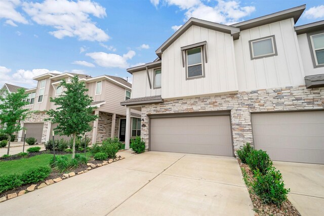 view of front of house featuring board and batten siding, an attached garage, concrete driveway, and stone siding