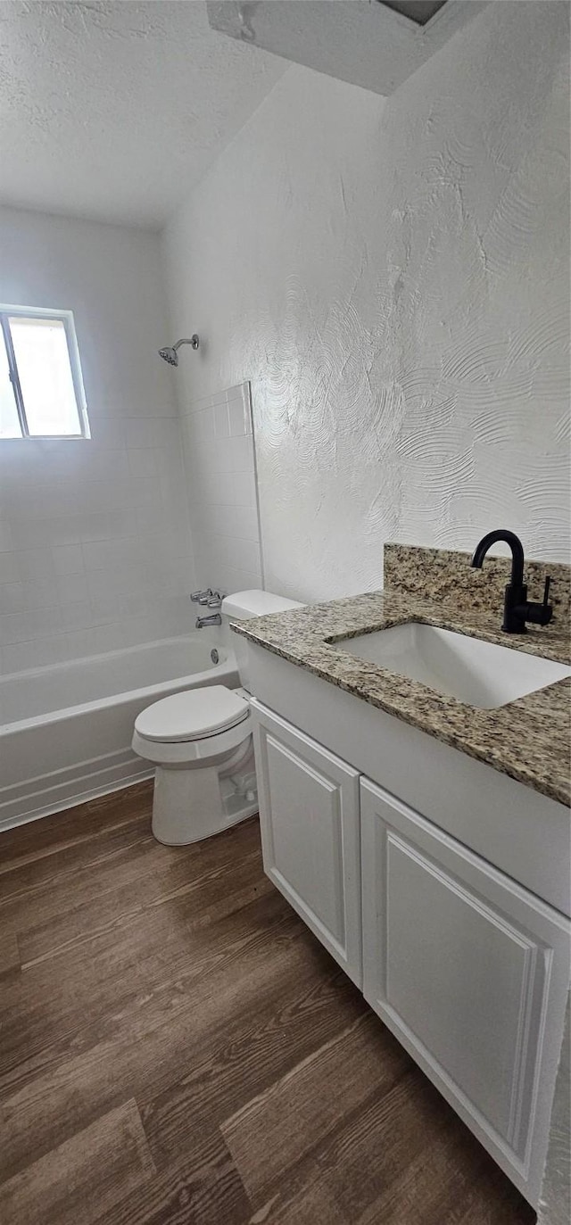 bathroom featuring vanity, toilet, wood finished floors, and bathtub / shower combination