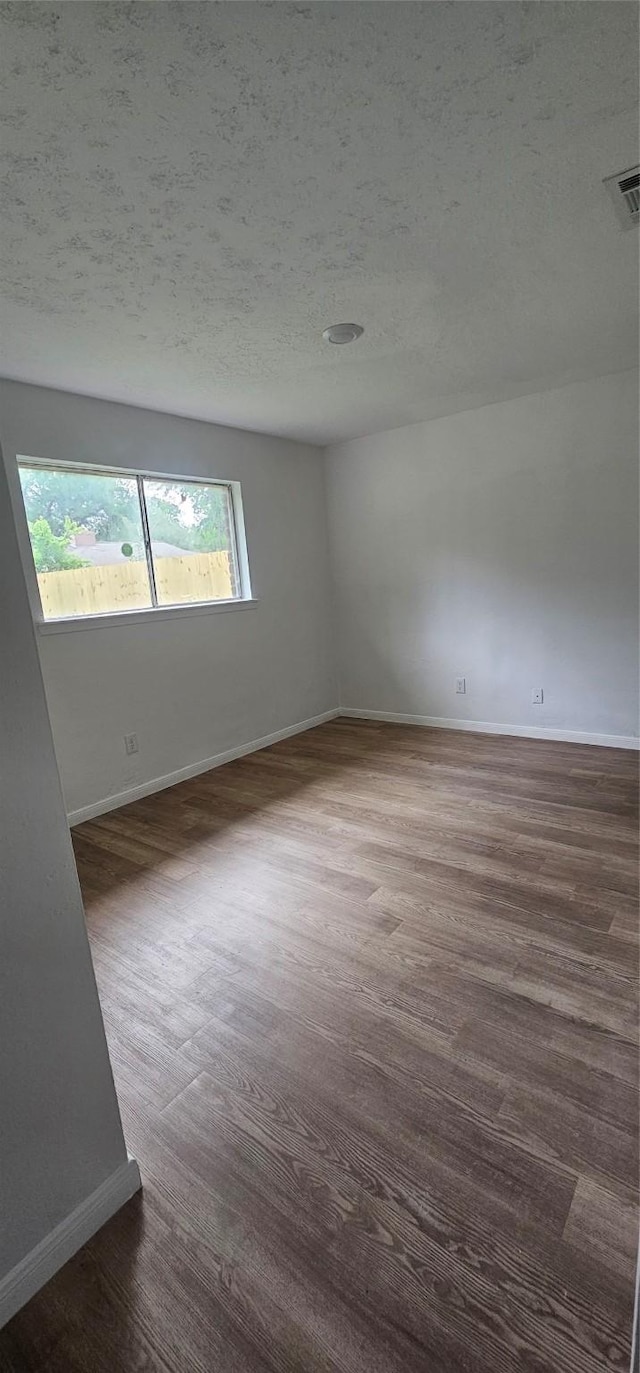 spare room featuring a textured ceiling, visible vents, and baseboards