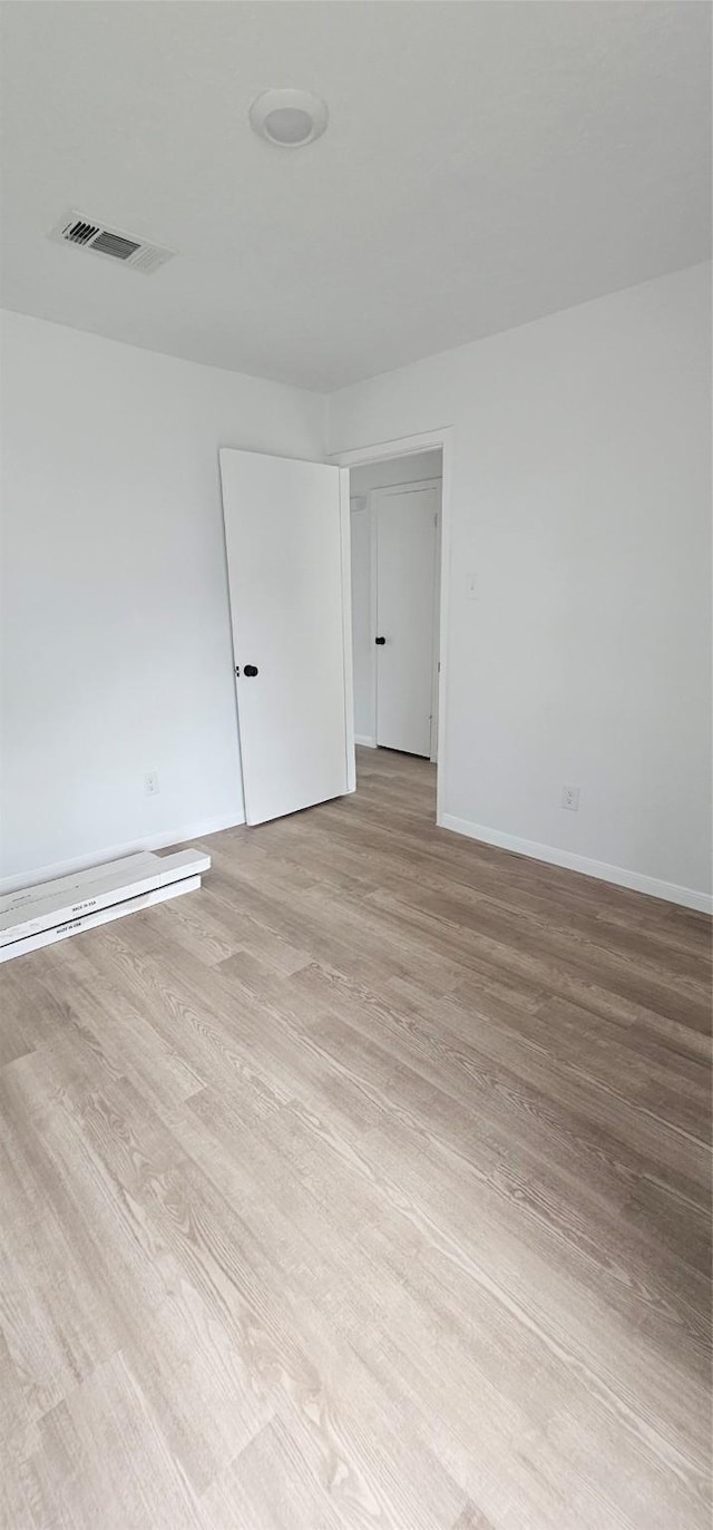 empty room with baseboards, visible vents, and light wood-style flooring
