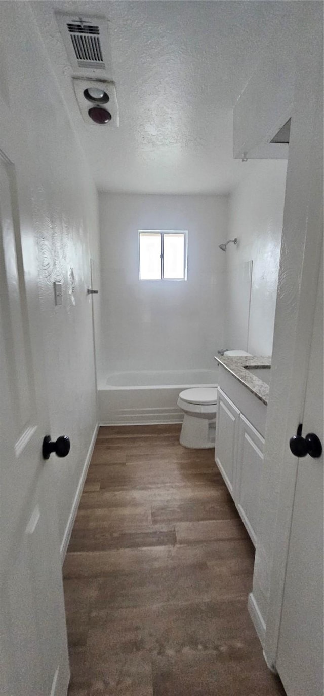 bathroom with shower / bath combination, a textured ceiling, wood finished floors, vanity, and toilet