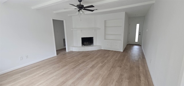 unfurnished living room with beamed ceiling, baseboards, light wood-style flooring, and a fireplace
